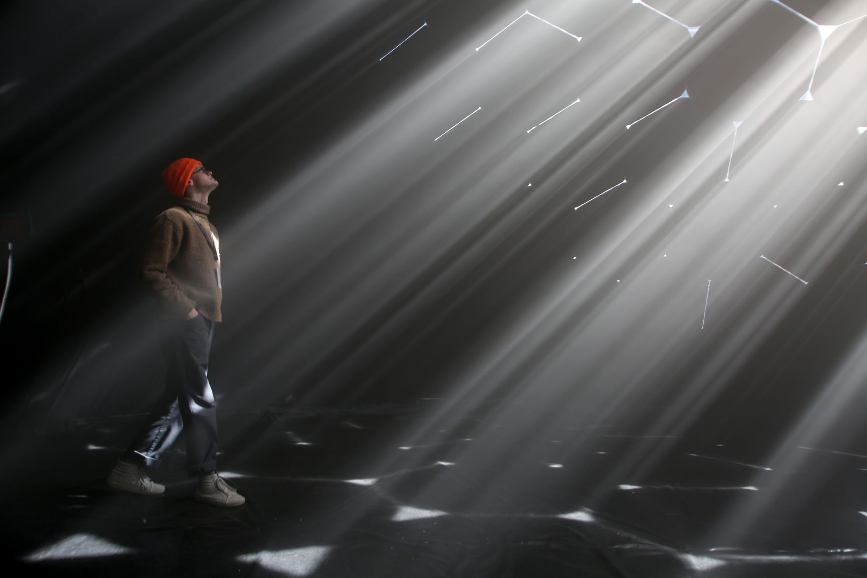 Levi Bedall, one of the three designers for the installation, walks between light beams on Friday